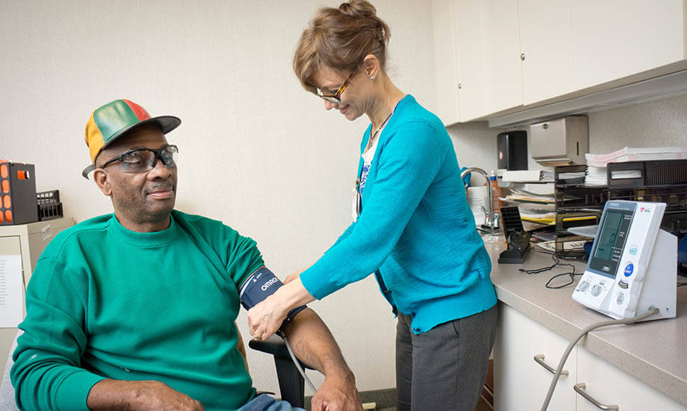 NIH clinical trial participant Curtis Minor has his blood pressure taken by Miriam Baird, R.N.  